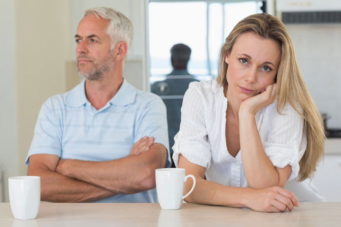 Woman refusing to be future caregiver for autistic stepbrother, sitting frustrated with man across the table in a kitchen. Woman refusing to be future caregiver for autistic stepbrother, sitting frustrated with man across the table in a kitchen.