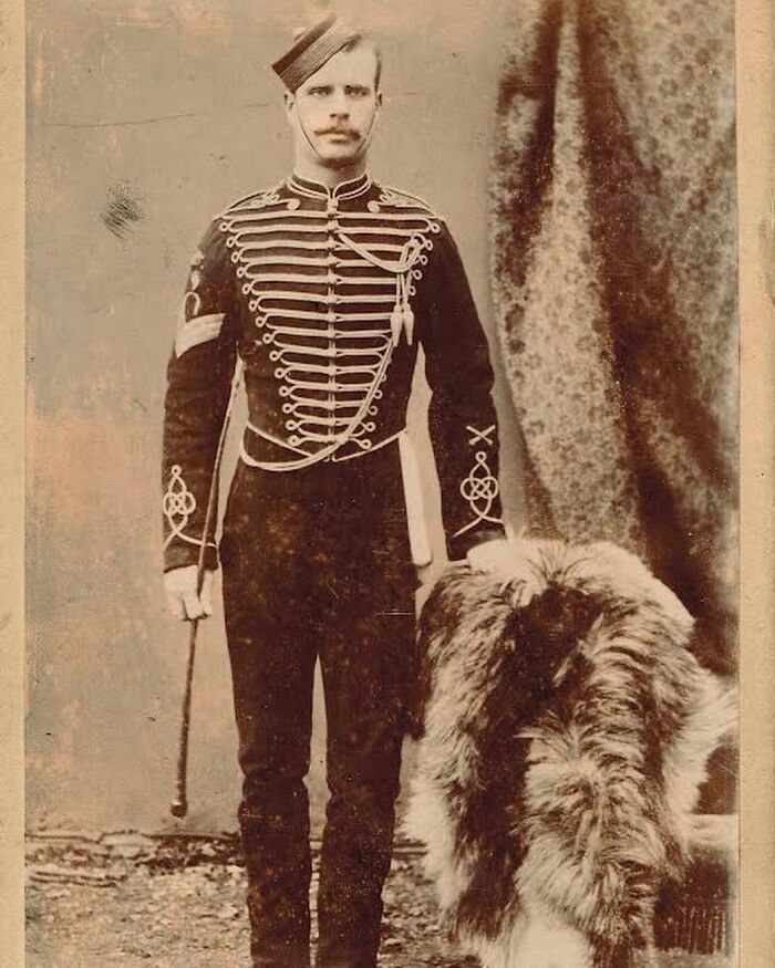 Victorian man in military uniform standing beside a large dog, showcasing handsome Victorian style and presence.