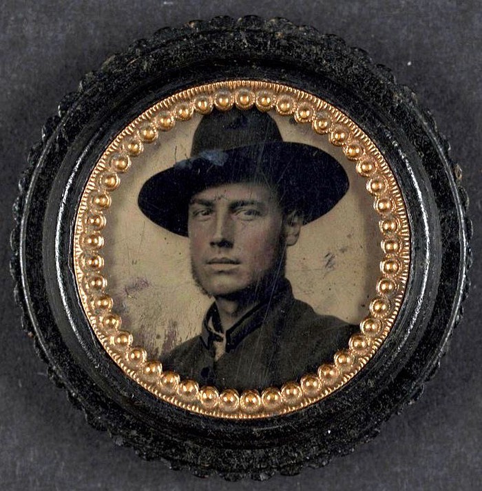 Portrait of a handsome Victorian man wearing a wide-brimmed hat inside a decorative circular frame.