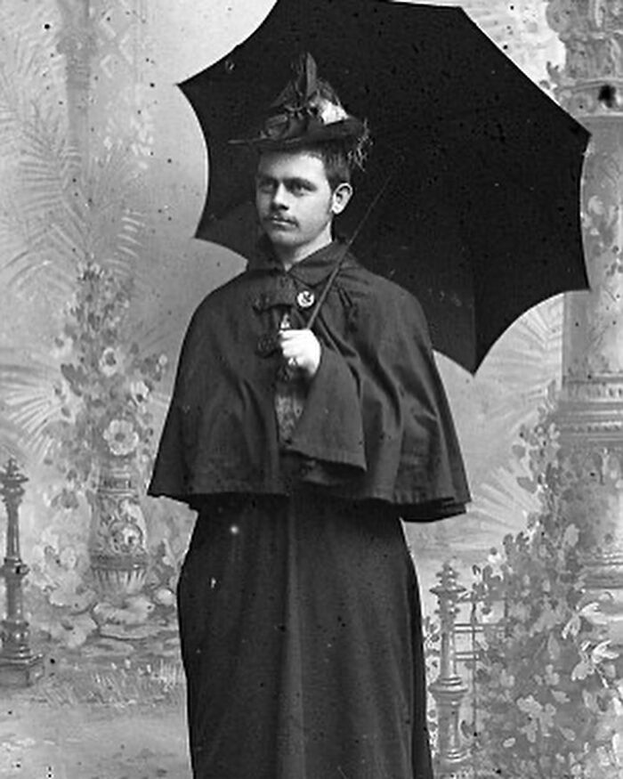 Victorian man dressed in period attire holding an umbrella, embodying classic style of handsome Victorian men.