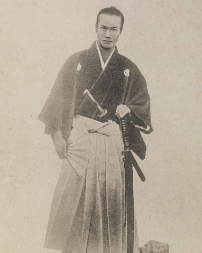 Victorian era man dressed in traditional Japanese attire holding a fan and sword, representing handsome Victorian men style.