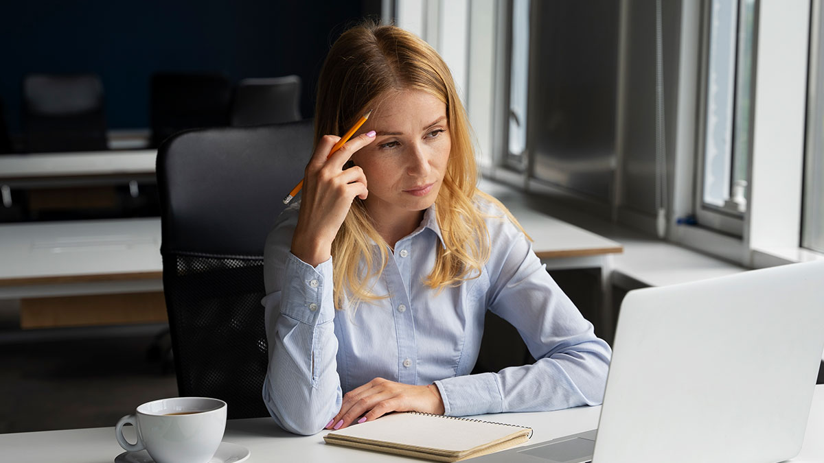 Woman in office looking concerned at laptop screen, representing toxic newbie conflict and HR issues.