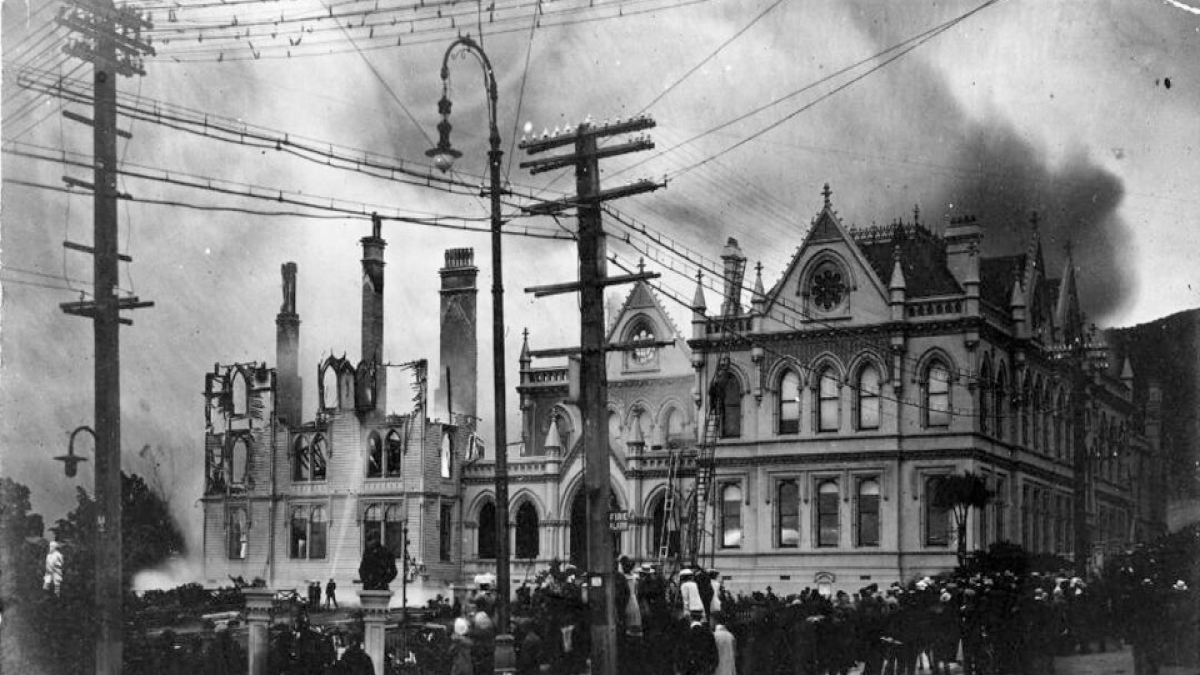 Crowd watches as historic building suffers fire damage with smoke rising, capturing a moment of preservation efforts.