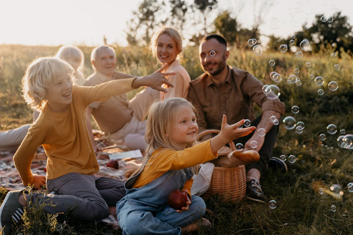 Childfree woman enjoying peaceful outdoor picnic while relatives and children play nearby during vacation getaway. Childfree woman enjoying peaceful outdoor picnic while relatives and children play nearby during vacation getaway.