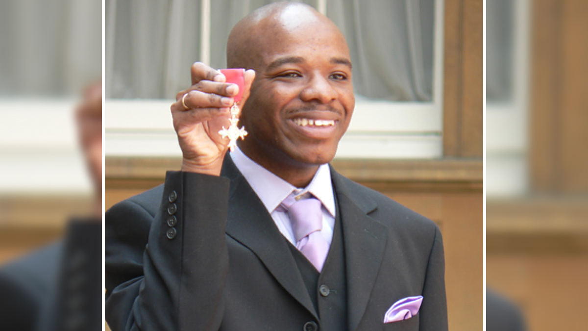 Man in suit smiling and holding a medal, celebrating an achievement among proof that superhumans walk among us