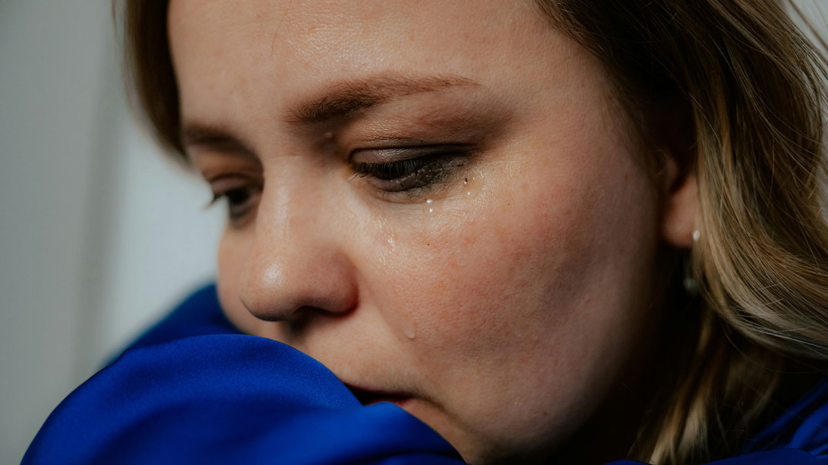Close-up of a woman crying, expressing emotional distress after husband confesses love for his colleague.