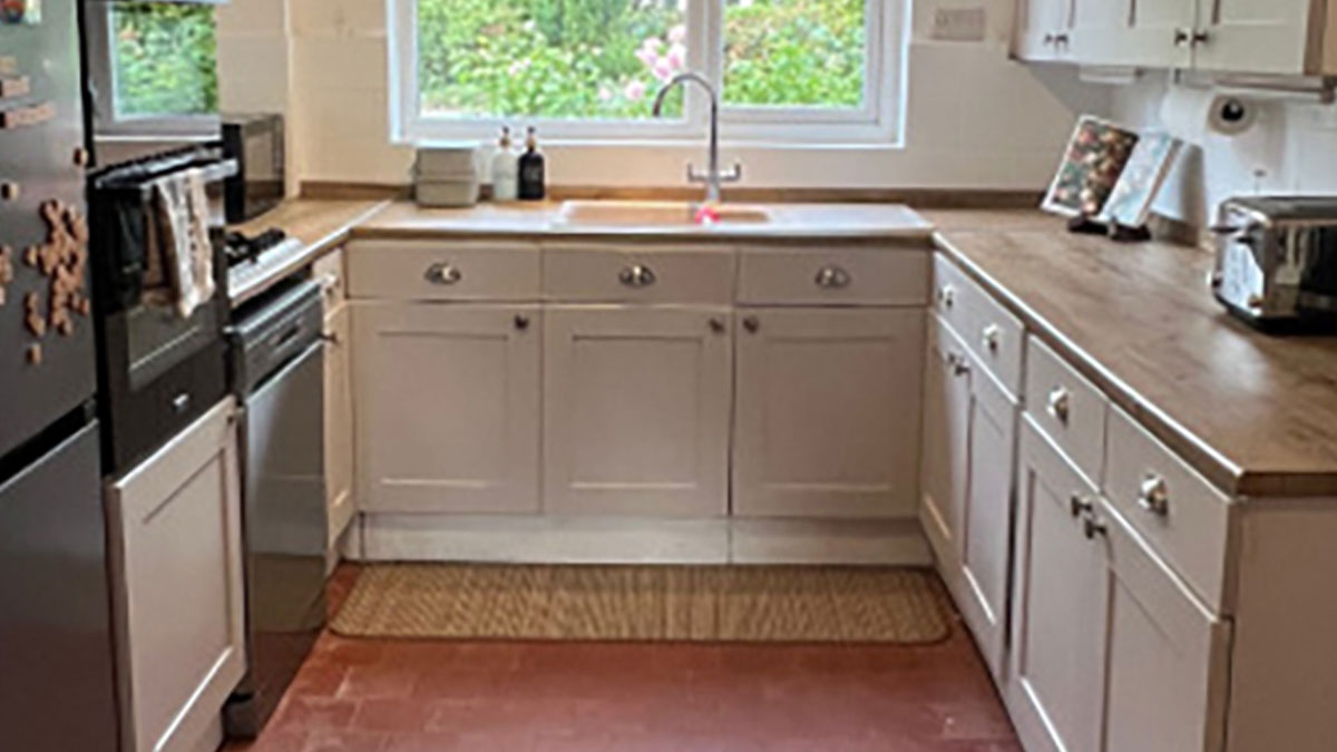Bright DIY kitchen makeover with wooden countertops, white cabinets, and a window overlooking greenery.