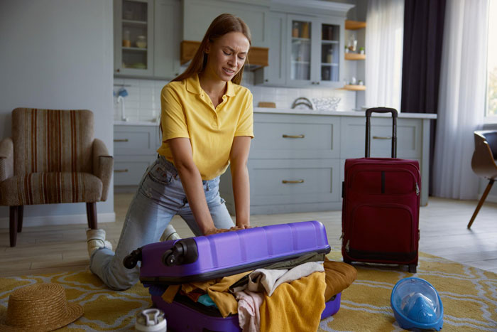 Woman struggling to close an overpacked suitcase, depicting tension in framing SIL and turning bro against his wife.