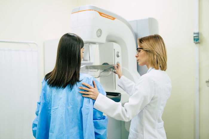 Woman in medical gown receiving diagnostic imaging while healthcare professional explains surgery details during appointment Woman in medical gown receiving diagnostic imaging while healthcare professional explains surgery details during appointment
