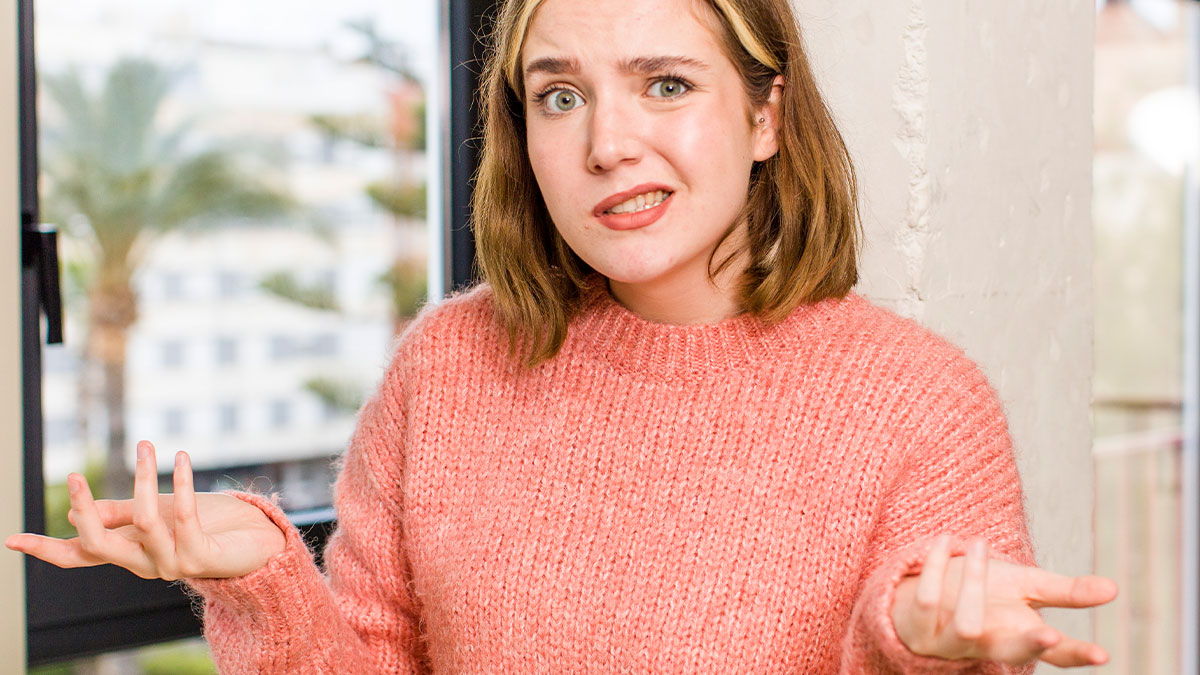 Woman in a pink sweater looking confused, wondering about explaining separation and divorce differences to her husband