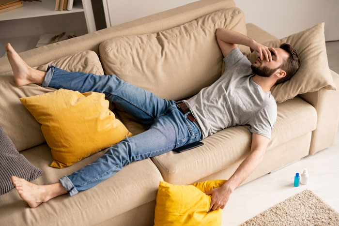 Man lying on sofa looking stressed, reflecting on friend’s compliment turning uncomfortable and wife insisting on hotel stay. Man lying on sofa looking stressed, reflecting on friend’s compliment turning uncomfortable and wife insisting on hotel stay.