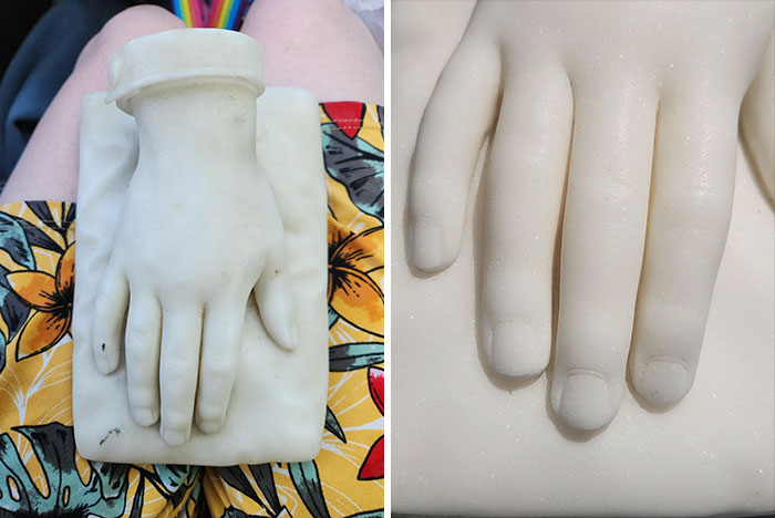 Close-up of a vintage marble hand sculpture thrift store find displayed on colorful fabric and textured surface.