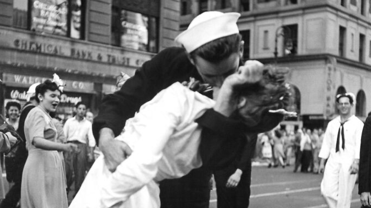 Iconic moment in history showing a sailor kissing a nurse in a busy city street with onlookers cheering.