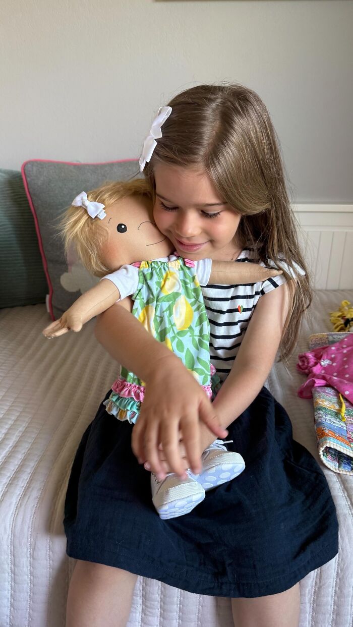 Young girl hugging a custom doll representing a rare health condition, designed to fit each child’s unique needs.