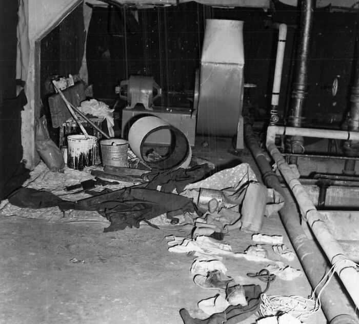 Cluttered maintenance area on Alcatraz with pipes, tools, and worn clothing showing harsh reality of life on the island.