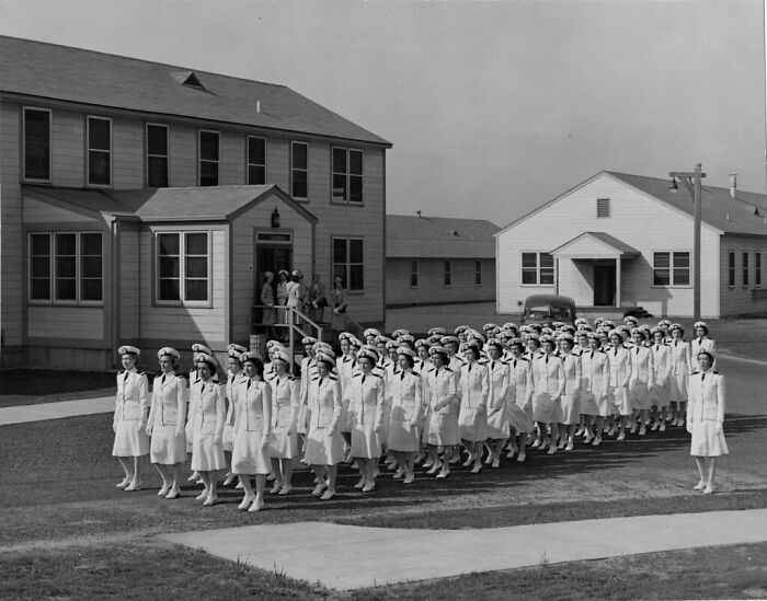 Group of women in uniform marching in formation outside military barracks in a rare WWII photo from the 1940s.