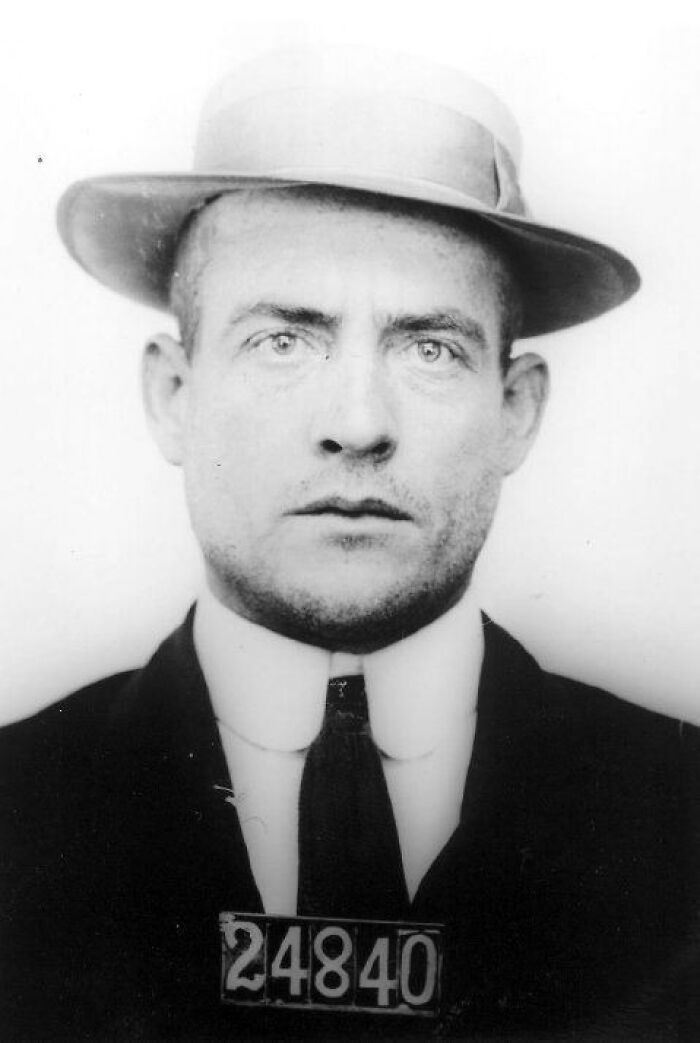 Black and white mugshot of an Alcatraz inmate wearing a hat and suit, illustrating harsh reality of life on Alcatraz.