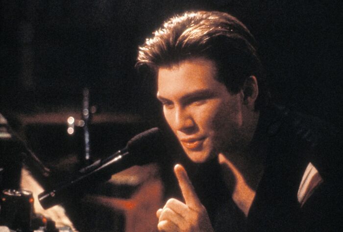 Young male actor performing passionately at a microphone, capturing the essence of iconic heartthrobs in classic cinema.