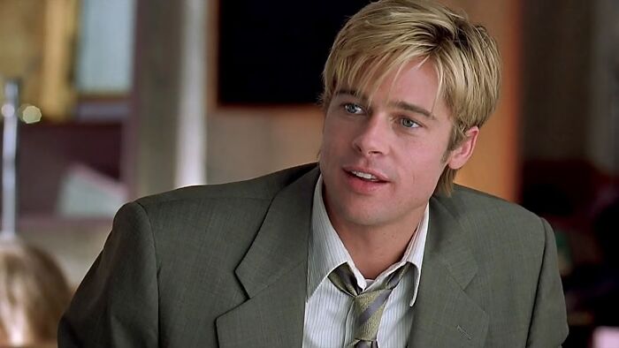 Young male actor with blonde hair wearing a grey suit and tie, representing classic heartthrobs from iconic photos.