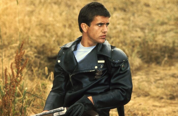 Young actor dressed in black leather jacket sitting outdoors, embodying a classic heartthrob style from iconic actor photos.