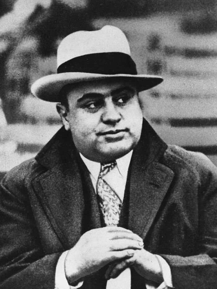 Black and white photo of a notorious mob boss wearing a suit and fedora, a key figure in mob boss history.