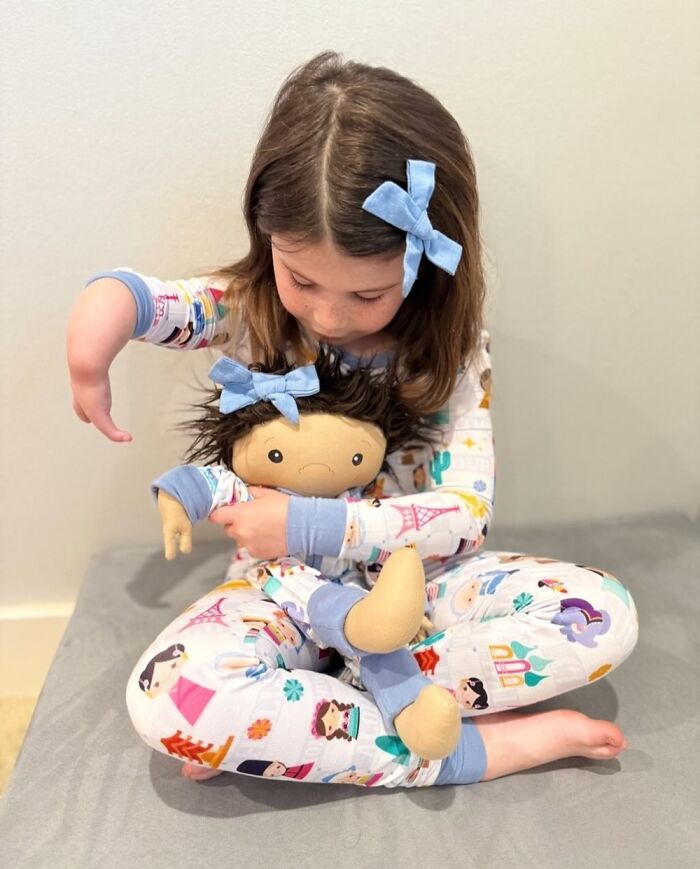 Young girl in pajamas holding a doll designed to represent rare health conditions, highlighting custom dolls for children.