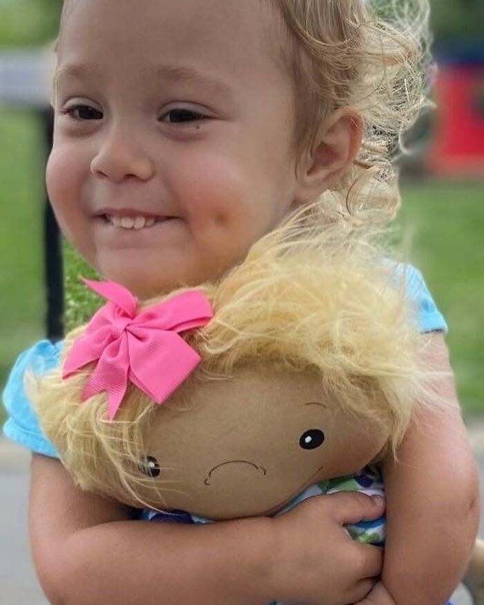 Smiling child hugging a doll designed to represent rare health conditions, showcasing personalized inclusive dolls for kids.