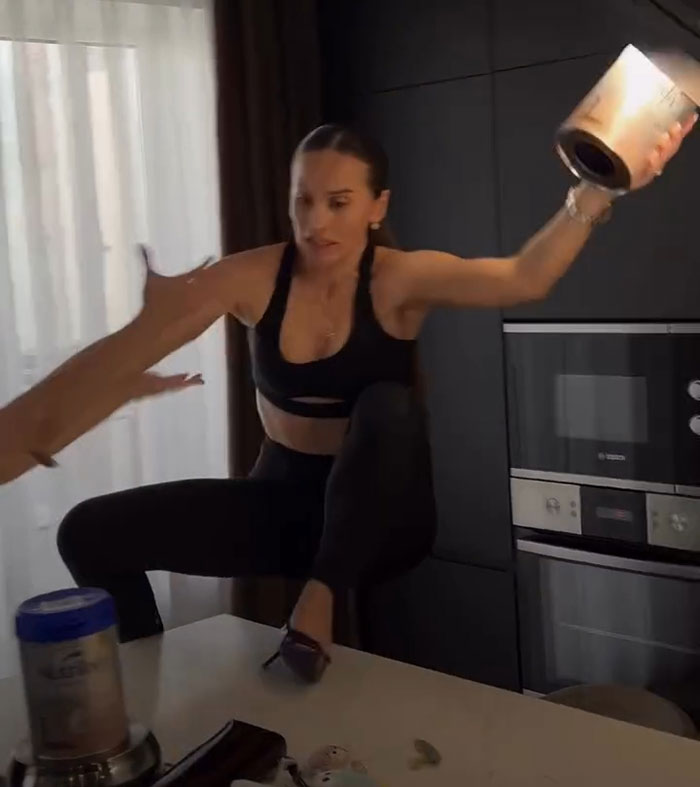 Woman in stilettos balancing on a kitchen counter while attempting a risky challenge, highlighting influencer spine injury risk. Woman in stilettos balancing on a kitchen counter while attempting a risky challenge, highlighting influencer spine injury risk.