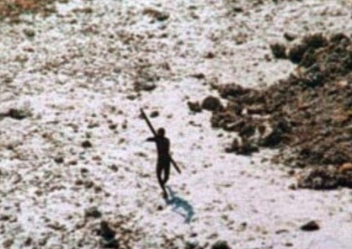 Silhouetted Indigenous tribe member walking with a spear on rocky terrain linked to influencer TikTok stunt controversy. Silhouetted Indigenous tribe member walking with a spear on rocky terrain linked to influencer TikTok stunt controversy.