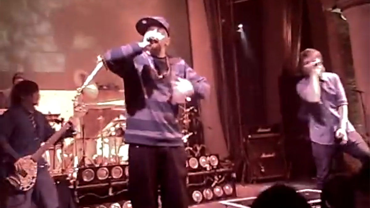 Live band performing on stage with vocalists and musicians in an energetic concert video context.