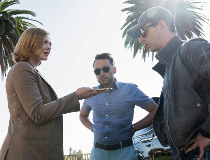 Three people outdoors sharing and discussing new facts, engaging in a lively conversation under palm trees.