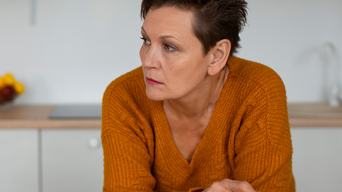 Woman in orange sweater looking worried, representing hiring managers dealing with difficult people in challenging situations.