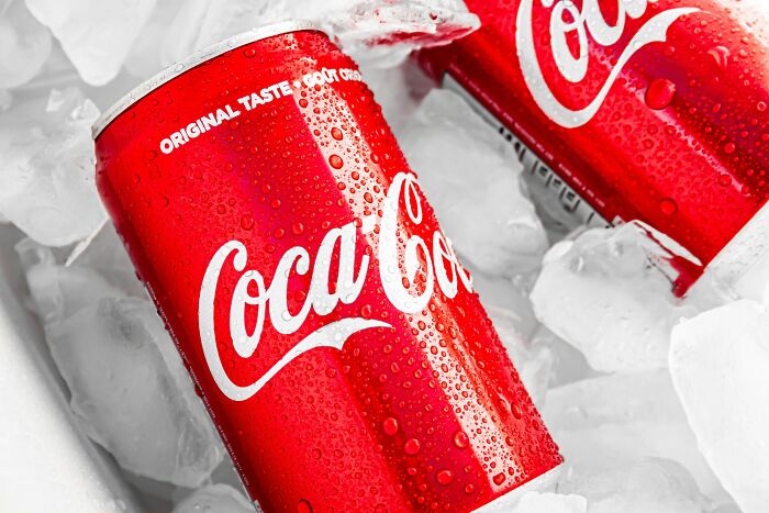 Two cold Coca-Cola cans chilling on ice, illustrating the concept of shopping and consumer habits.
