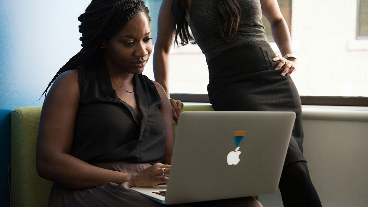 Two professional women collaborating on a laptop, sharing insightful truths about their jobs in an office setting.