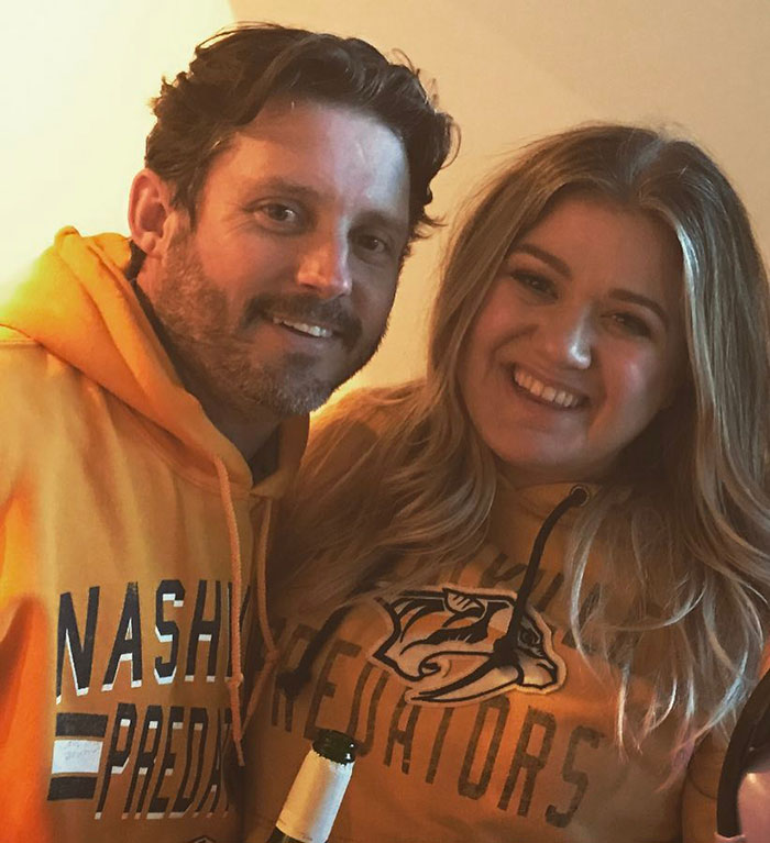 Man and woman smiling together wearing Nashville Predators hoodies, representing Kelly Clarkson’s family after ex’s passing. Man and woman smiling together wearing Nashville Predators hoodies, representing Kelly Clarkson’s family after ex’s passing.