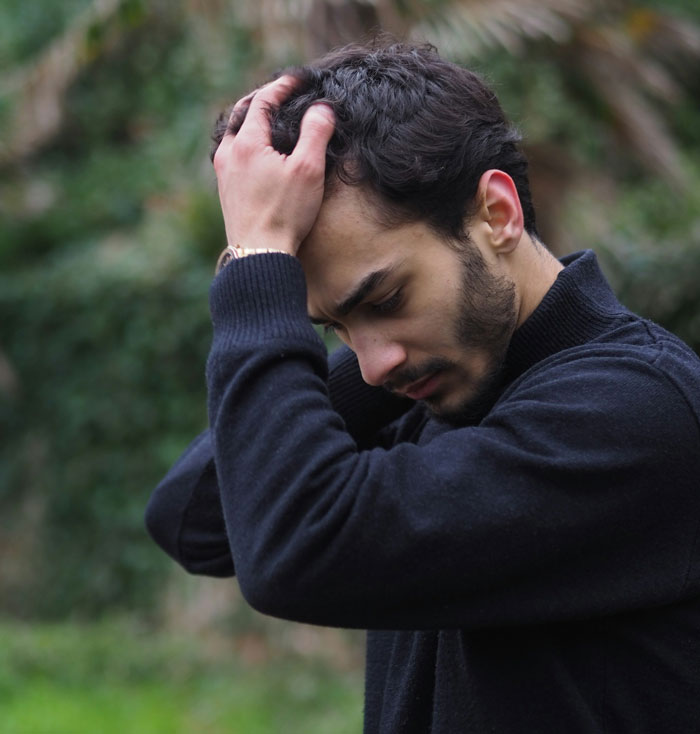 Man with worried expression holding his head outdoors, symbolizing struggle to win over fiancee’s kids. Man with worried expression holding his head outdoors, symbolizing struggle to win over fiancee’s kids.
