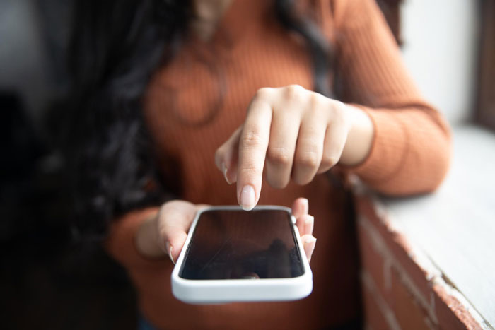 Person using smartphone indoors, illustrating frustration with villainous vacuum cleaner salespeople interaction. Person using smartphone indoors, illustrating frustration with villainous vacuum cleaner salespeople interaction.