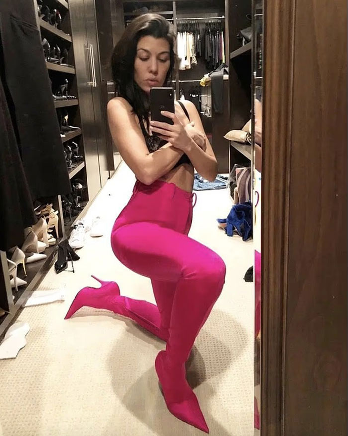 Woman in bright pink boots and pants posing in a messy walk-in closet, capturing a wild video sparking major worry. Woman in bright pink boots and pants posing in a messy walk-in closet, capturing a wild video sparking major worry.