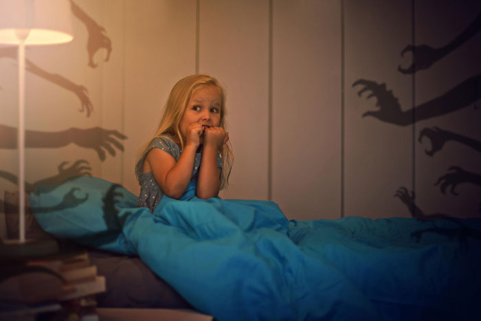 Young girl on bunk bed looking scared as creepy hands’ shadows appear on bedroom walls at night. Young girl on bunk bed looking scared as creepy hands’ shadows appear on bedroom walls at night.