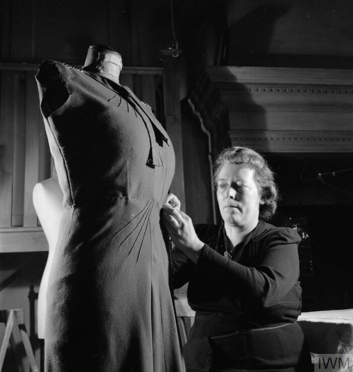 British woman sewing a dress on a mannequin, showcasing how British women kept their style during WWII restrictions.