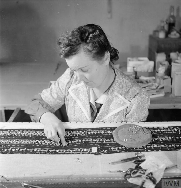 British woman sewing patterned fabric, illustrating how British women kept their style during WWII restrictions.