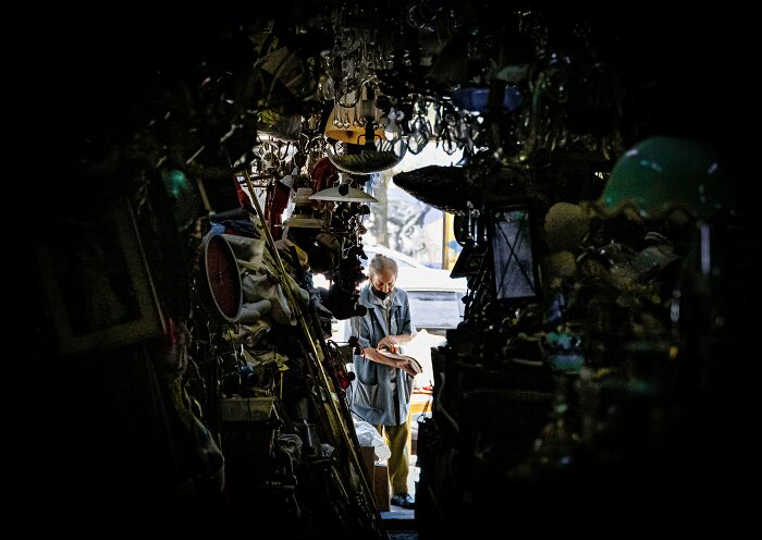 A cluttered, dimly lit room filled with various objects and an older man standing near the entrance, highlighting grossest things witnessed.