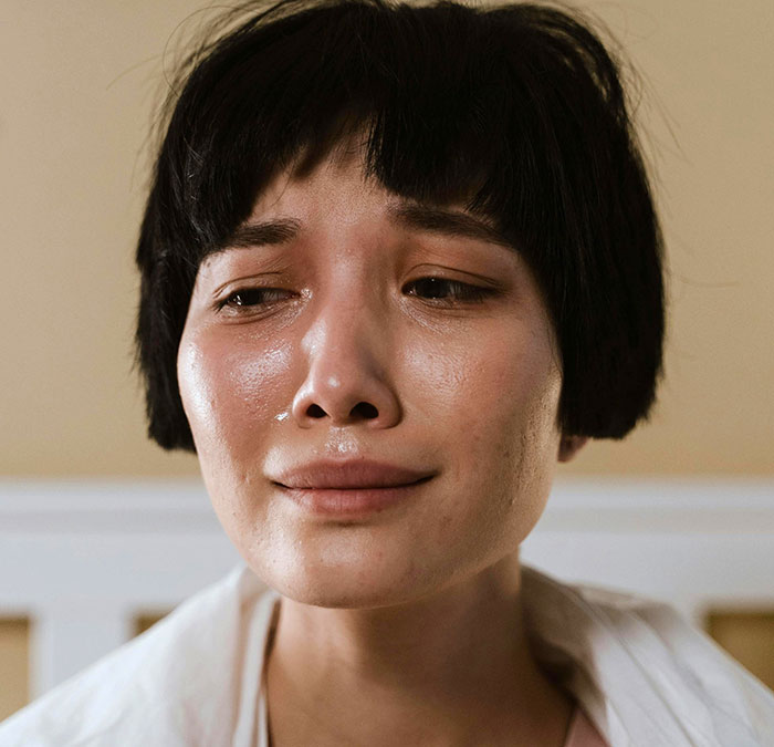 Sad woman with short hair shedding a tear, reflecting a widow wanting to move back to her home country. Sad woman with short hair shedding a tear, reflecting a widow wanting to move back to her home country.