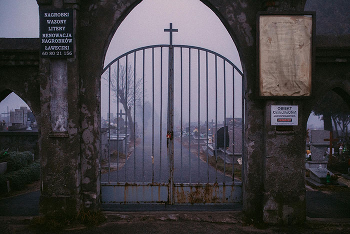 Rusty iron gate with cross at entrance to foggy cemetery, symbolizing widow’s legal battle to move back with kids. Rusty iron gate with cross at entrance to foggy cemetery, symbolizing widow’s legal battle to move back with kids.