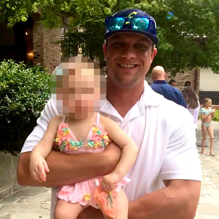 Man in sunglasses holding child outdoors, related to father assaults friend over refusal to share breast milk. Man in sunglasses holding child outdoors, related to father assaults friend over refusal to share breast milk.