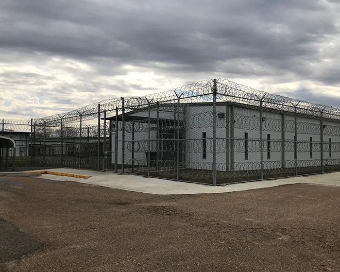 Prison building surrounded by barbed wire fence under cloudy sky, related to father-of-two assault case. Prison building surrounded by barbed wire fence under cloudy sky, related to father-of-two assault case.