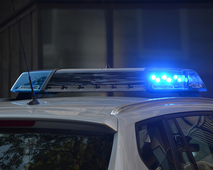 Police car with flashing blue lights at night, related to assault involving refusal of breast milk. Police car with flashing blue lights at night, related to assault involving refusal of breast milk.