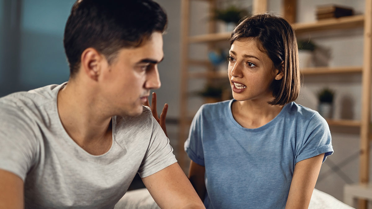 Couple having a serious discussion, woman expressing concern while man listens, highlighting tattoo disagreement tension.