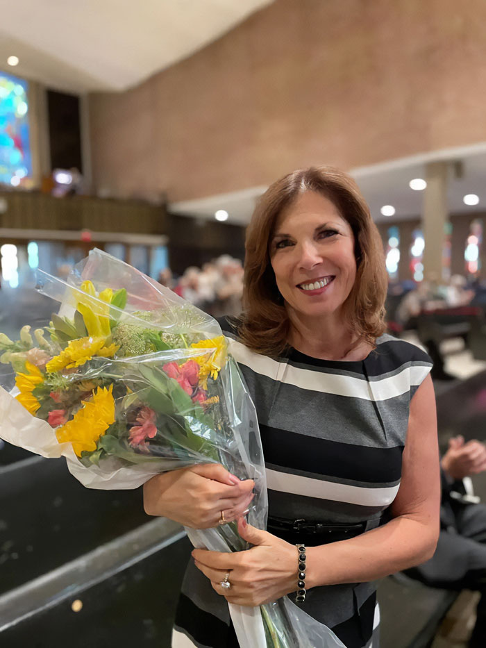 Woman smiling and holding a bouquet of flowers in a public setting related to Minneapolis school attacker mother debate. Woman smiling and holding a bouquet of flowers in a public setting related to Minneapolis school attacker mother debate.