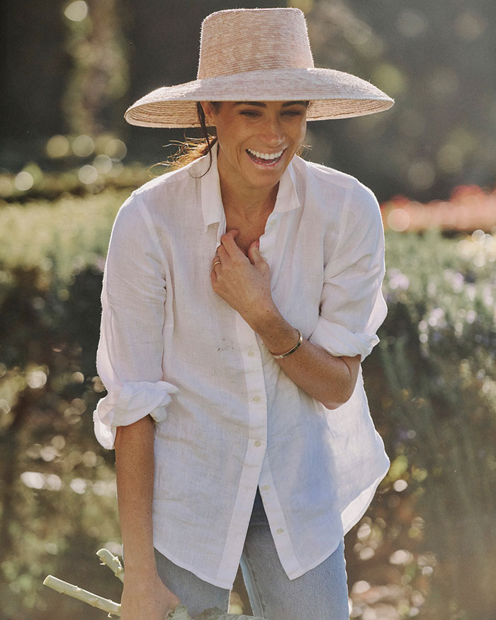 Meghan Markle in a white shirt and wide-brim hat, smiling outdoors while addressing cooking show accusations. Meghan Markle in a white shirt and wide-brim hat, smiling outdoors while addressing cooking show accusations.